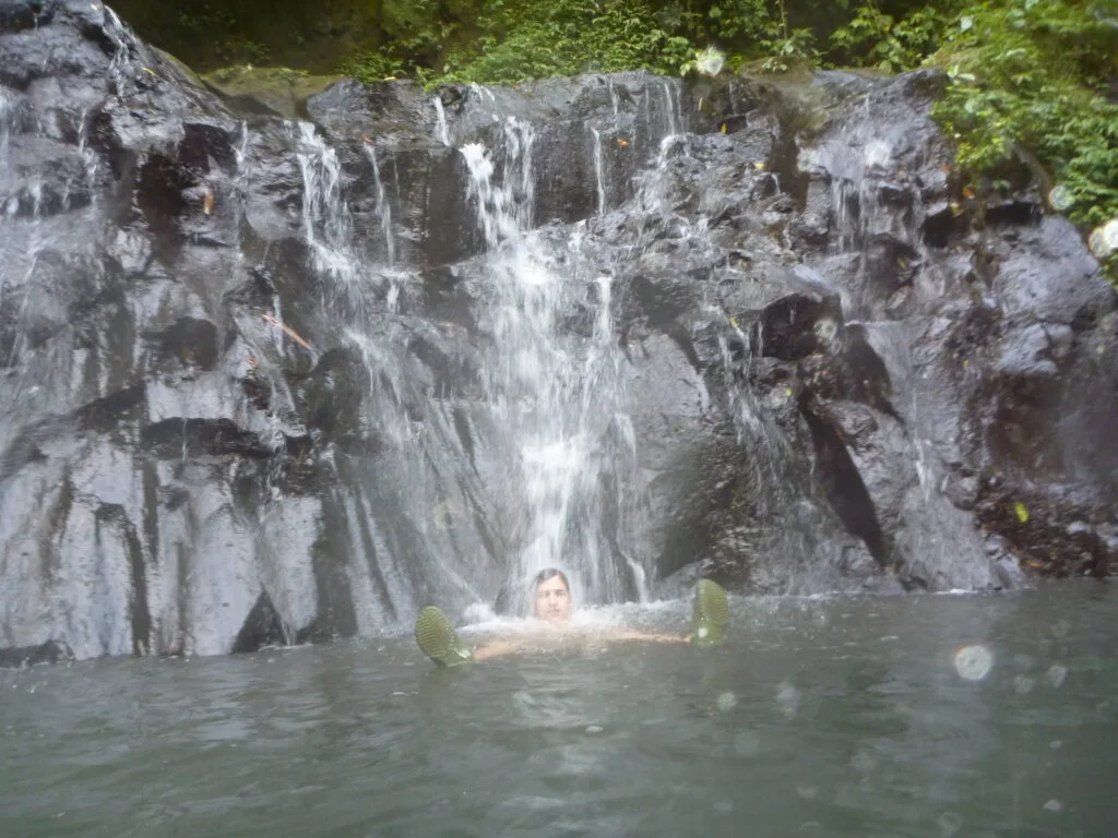 Person floating under waterfall