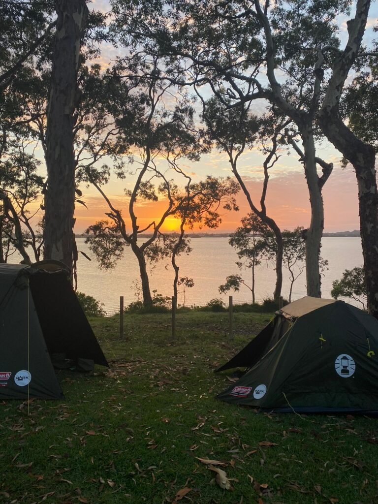 Sun rises behind two tents at Wangi Point Holiday Park over Lake Macquarie